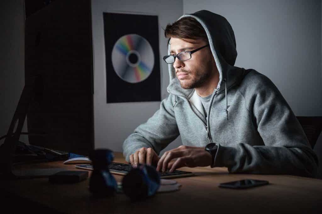 Thoughtful man in glasses and hoodie working on computer to make money online