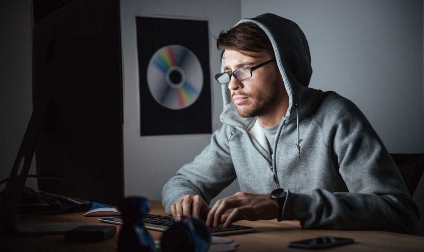 Thoughtful man in glasses and hoodie working on computer to make money online