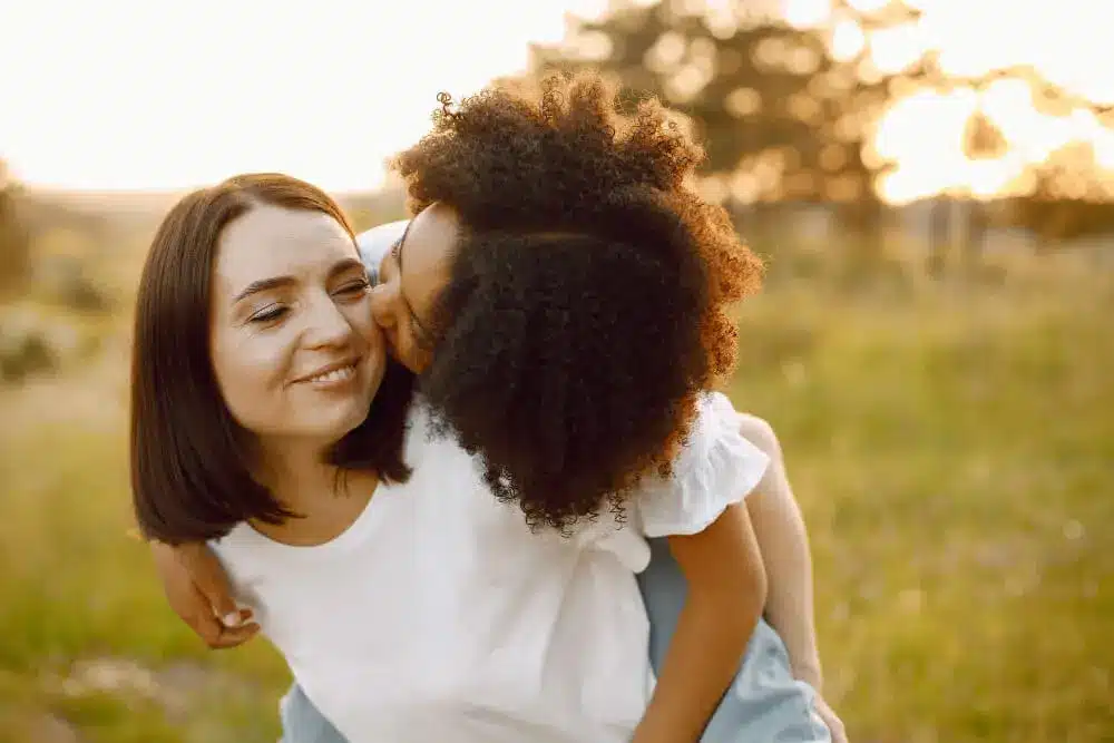 photo african american daughter kiss her caucasian mother girl has black curly hair