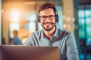 Handsome young smiley male with headphones on working on customer support. Generative AI