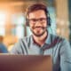 Handsome young smiley male with headphones on working on customer support. Generative AI
