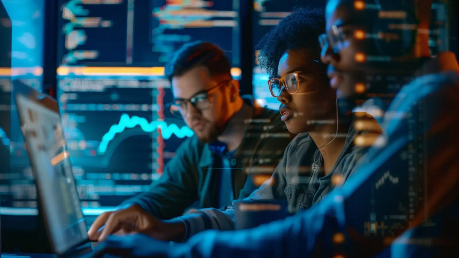 Portrait of Two Diverse Developers Using Laptop Computer Discussing Lines of Code that Appear on Big Screens Surrounding Them. Male and Female Programmers Creating Software Together and Fixing Bugs